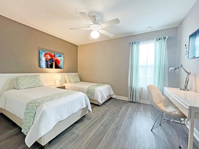 bedroom with ceiling fan, wood-type flooring, and a textured ceiling