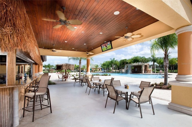 view of patio / terrace featuring pool water feature, ceiling fan, a bar, and a community pool