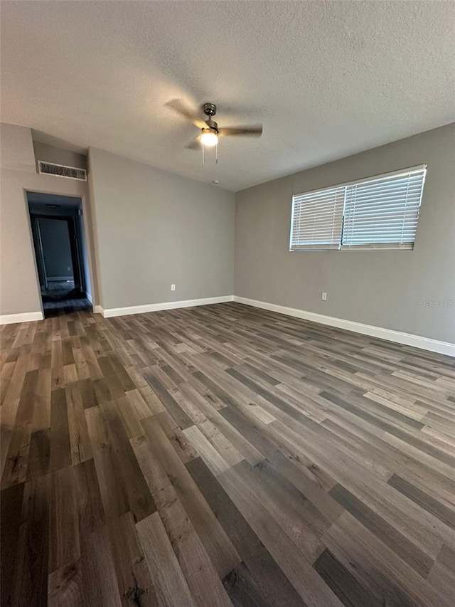 empty room with a textured ceiling, dark hardwood / wood-style floors, and ceiling fan