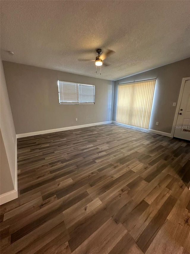 unfurnished room with ceiling fan, dark wood-type flooring, and a textured ceiling