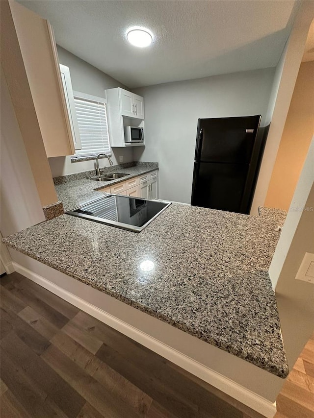 kitchen with kitchen peninsula, a textured ceiling, black appliances, sink, and white cabinetry