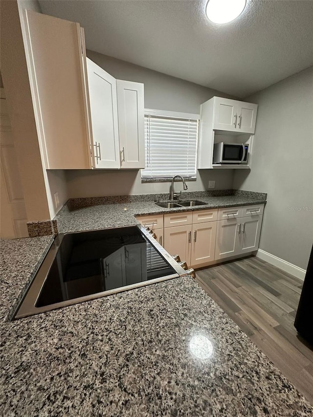 kitchen featuring sink, white cabinets, dark stone counters, and a textured ceiling