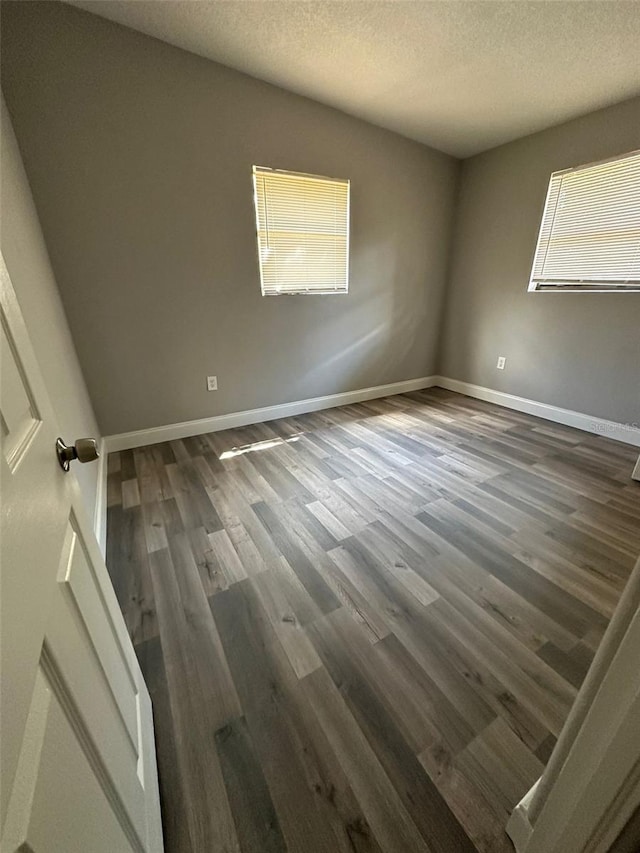 unfurnished room with dark wood-type flooring and a textured ceiling