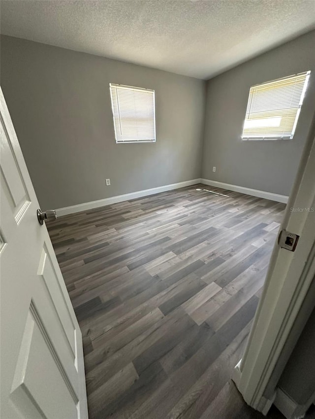 unfurnished room featuring a textured ceiling and dark hardwood / wood-style floors