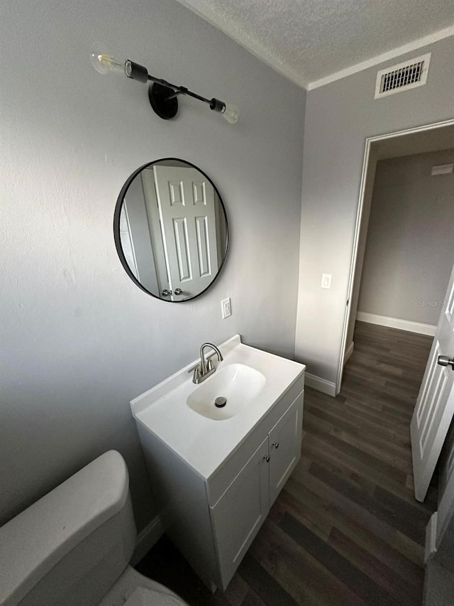 bathroom with vanity, a textured ceiling, hardwood / wood-style flooring, and toilet