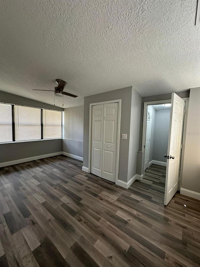 unfurnished bedroom with a textured ceiling, ceiling fan, a closet, and dark hardwood / wood-style floors