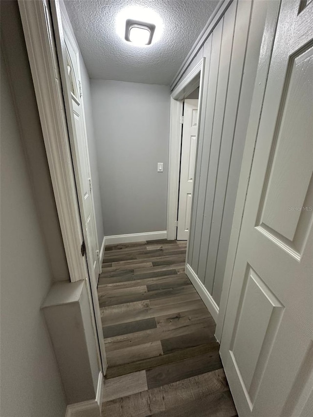 hallway with dark hardwood / wood-style flooring and a textured ceiling