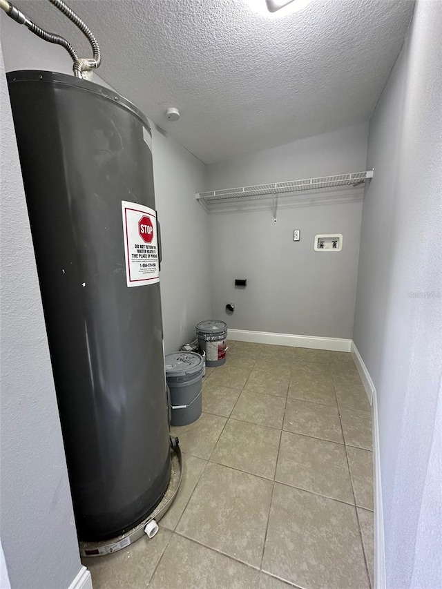 clothes washing area featuring washer hookup, electric dryer hookup, electric water heater, a textured ceiling, and light tile patterned flooring