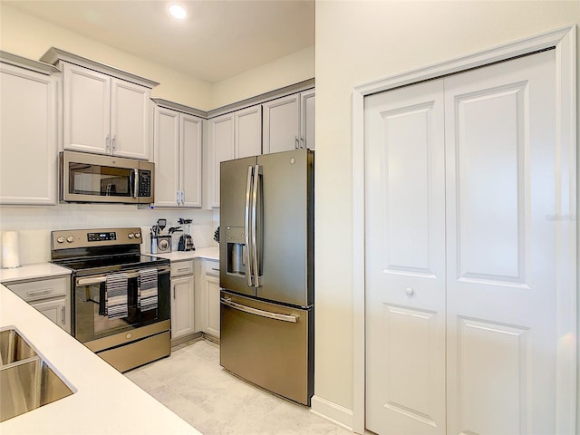 kitchen featuring appliances with stainless steel finishes, backsplash, light tile flooring, and gray cabinetry