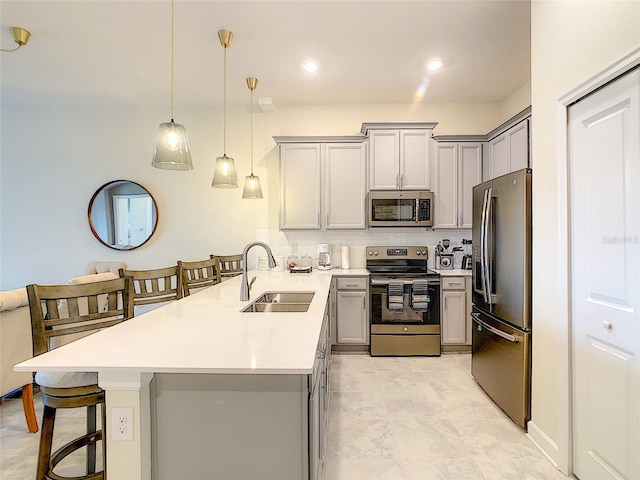 kitchen featuring kitchen peninsula, a breakfast bar area, gray cabinets, appliances with stainless steel finishes, and sink