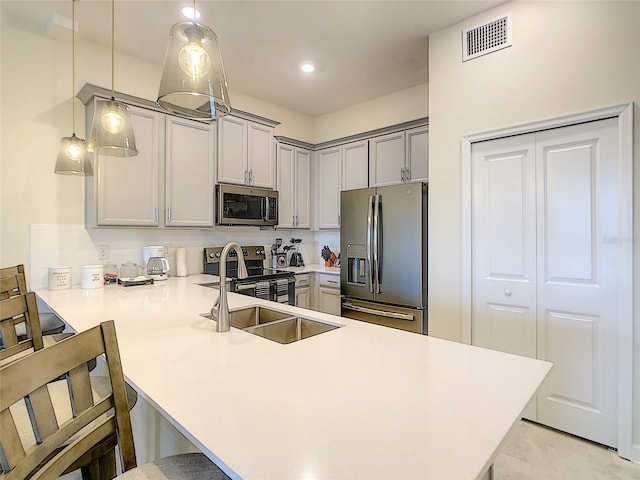 kitchen featuring stainless steel appliances, gray cabinets, a breakfast bar area, kitchen peninsula, and decorative light fixtures