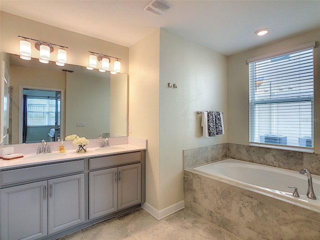 bathroom featuring tile floors, dual sinks, tiled bath, and vanity with extensive cabinet space