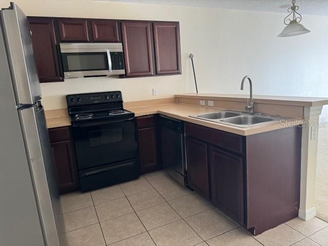 kitchen with hanging light fixtures, black appliances, kitchen peninsula, sink, and light tile flooring