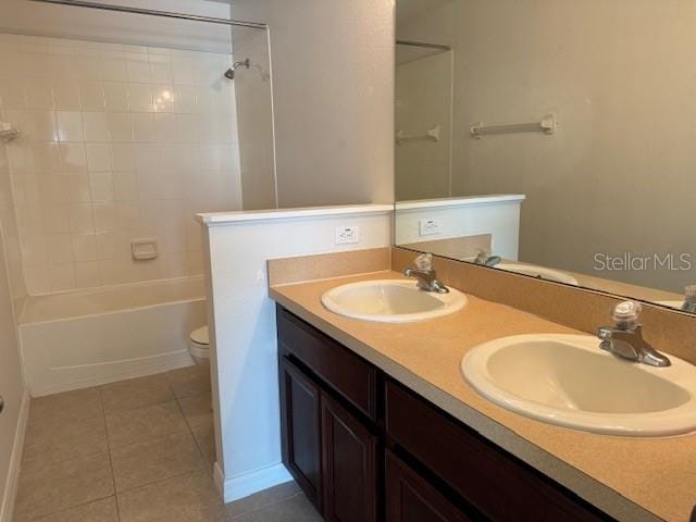 full bathroom featuring tile floors, tub / shower combination, toilet, and dual bowl vanity