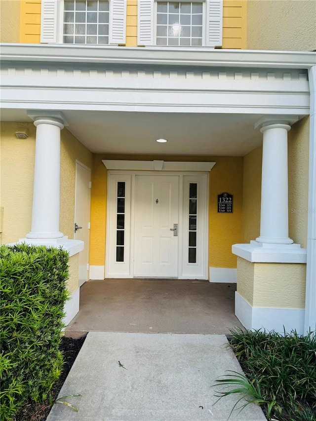 view of exterior entry with covered porch and stucco siding