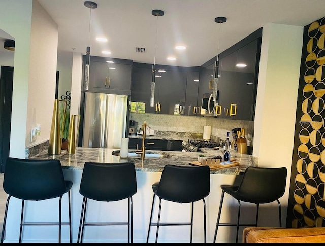 kitchen with appliances with stainless steel finishes, pendant lighting, kitchen peninsula, and gray cabinets