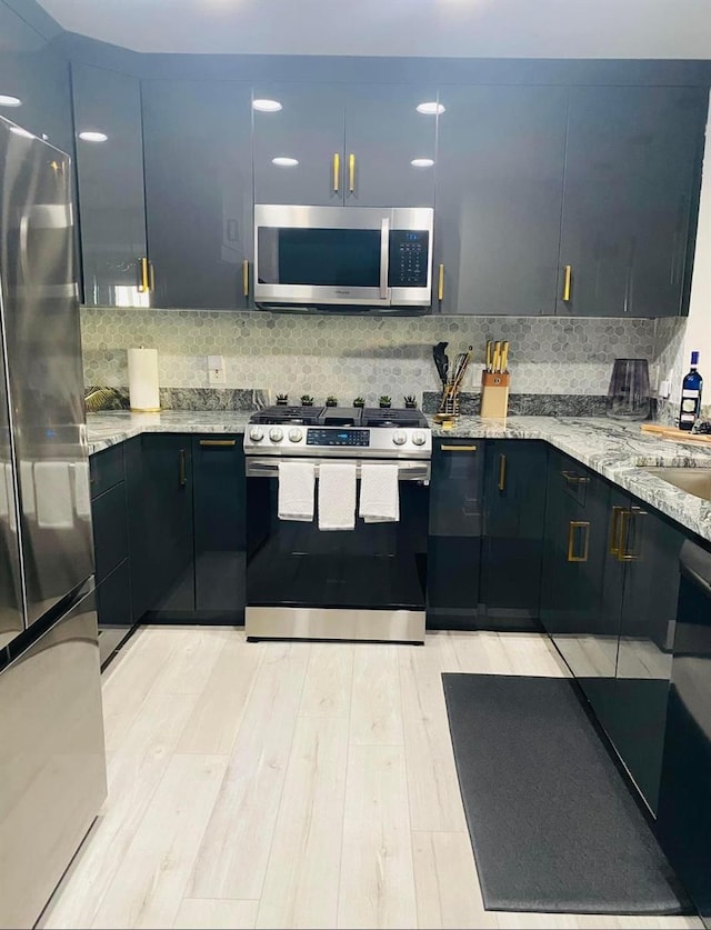 kitchen featuring stainless steel appliances, sink, light stone counters, light hardwood / wood-style flooring, and decorative backsplash