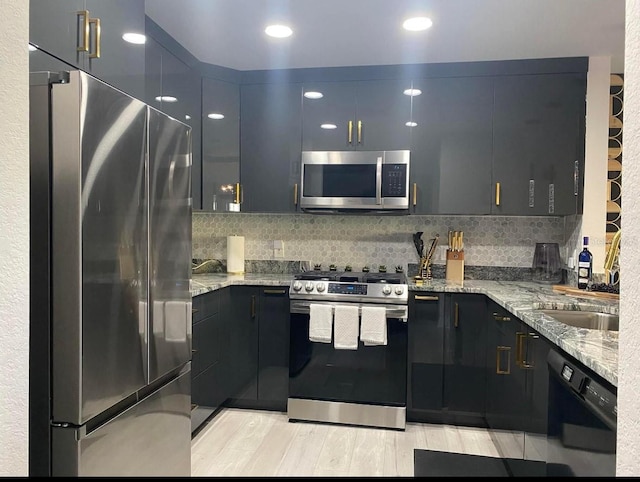 kitchen with stainless steel appliances, sink, backsplash, and light stone counters