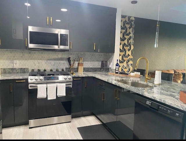 kitchen featuring appliances with stainless steel finishes, sink, backsplash, and light stone countertops