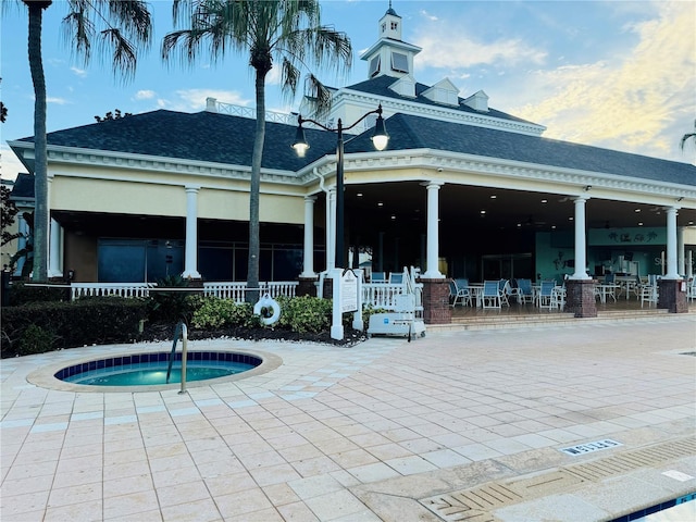 rear view of property featuring a hot tub