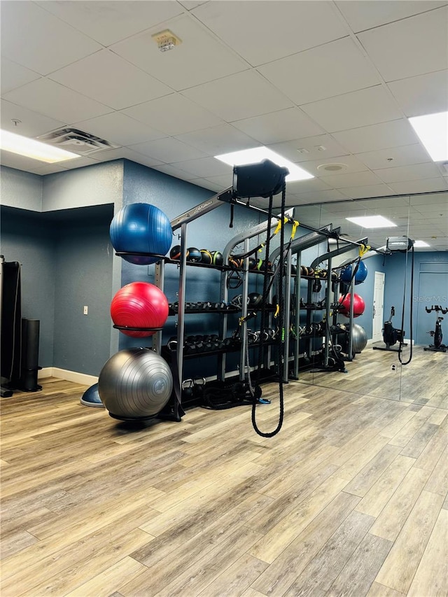 gym featuring hardwood / wood-style floors and a drop ceiling