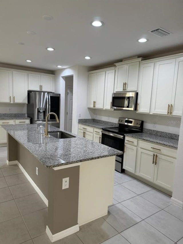 kitchen with appliances with stainless steel finishes, sink, white cabinetry, and an island with sink