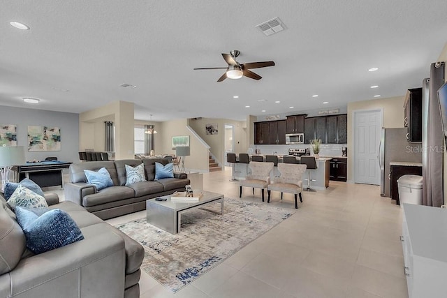 tiled living room featuring ceiling fan with notable chandelier