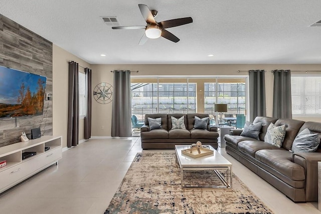 living room with ceiling fan, a textured ceiling, and light tile patterned floors