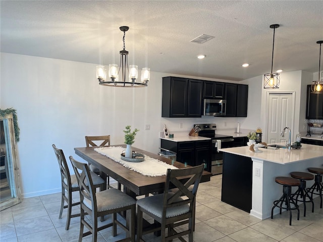 tiled dining space featuring a notable chandelier, sink, and a textured ceiling