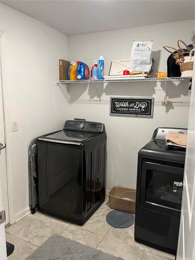 laundry area featuring washing machine and clothes dryer and light tile flooring