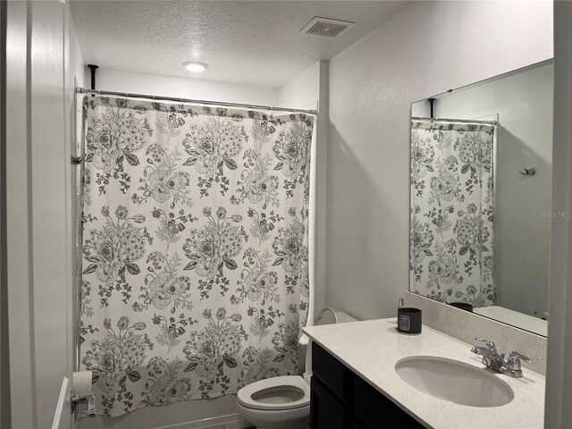 bathroom with vanity with extensive cabinet space, a textured ceiling, and toilet