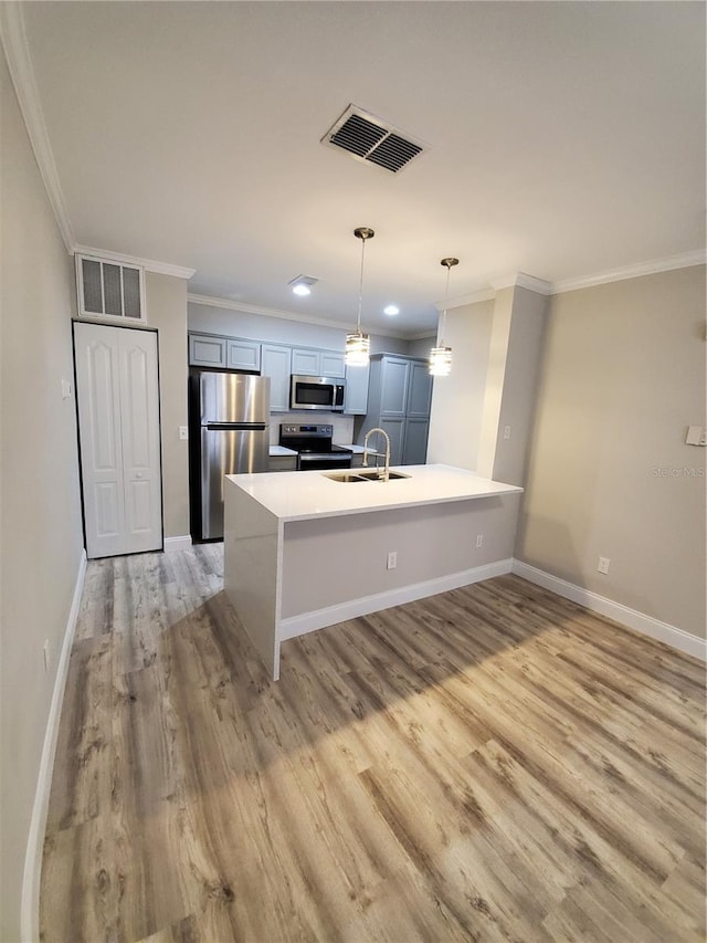 kitchen featuring appliances with stainless steel finishes, pendant lighting, sink, ornamental molding, and light wood-type flooring