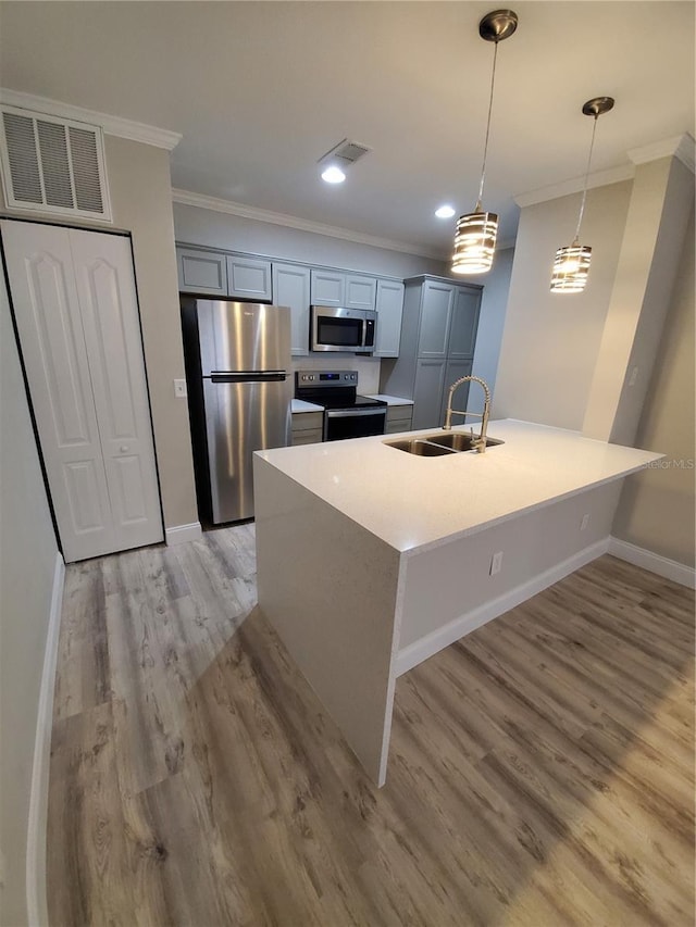 kitchen with sink, crown molding, pendant lighting, stainless steel appliances, and a kitchen island with sink