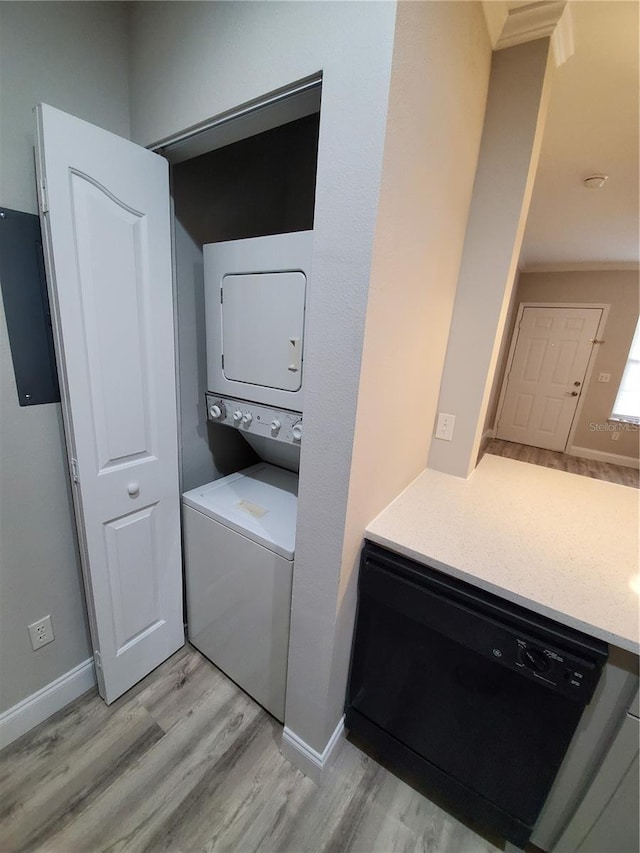 laundry area with light hardwood / wood-style flooring and stacked washer and clothes dryer