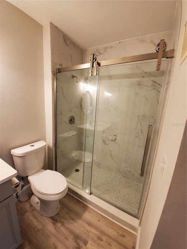 bathroom featuring hardwood / wood-style flooring, vanity, toilet, and a shower with shower door