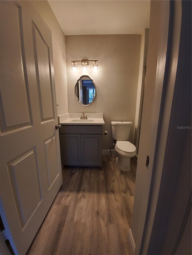 bathroom featuring wood-type flooring, toilet, and vanity