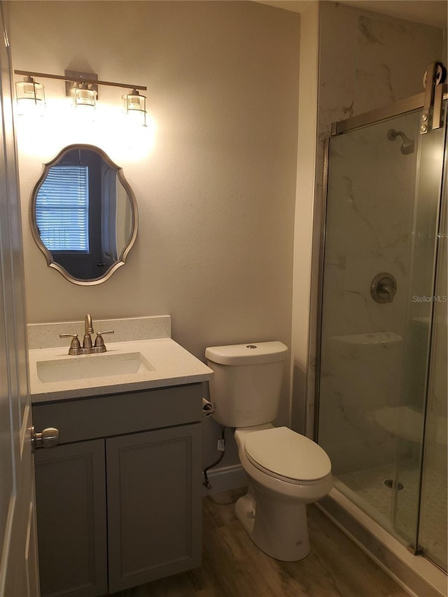 bathroom with vanity, hardwood / wood-style floors, a shower with shower door, and toilet