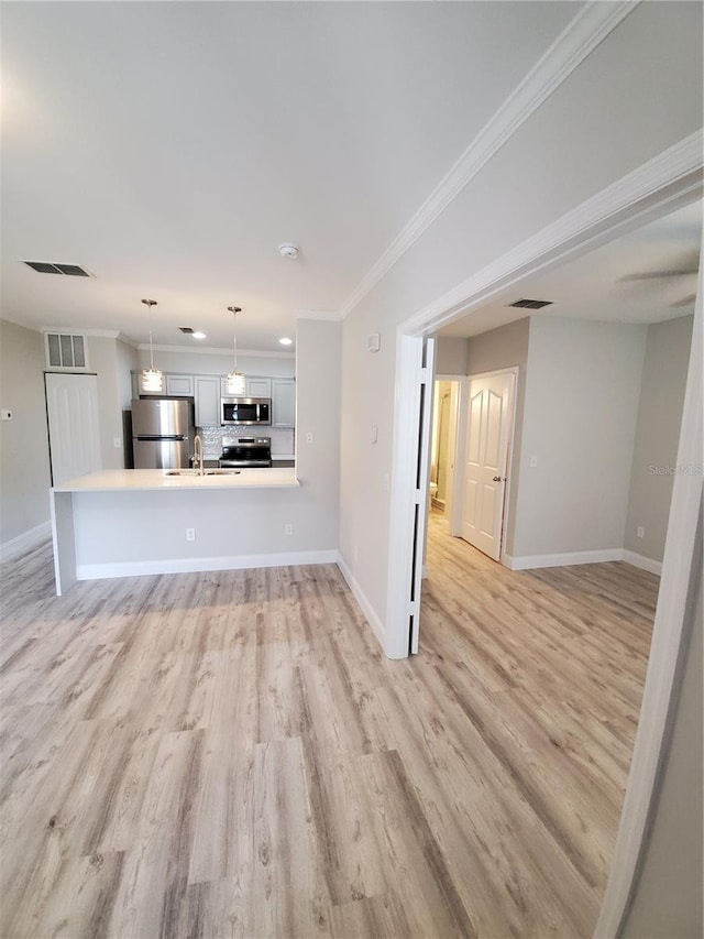 unfurnished living room with sink, crown molding, and light hardwood / wood-style flooring