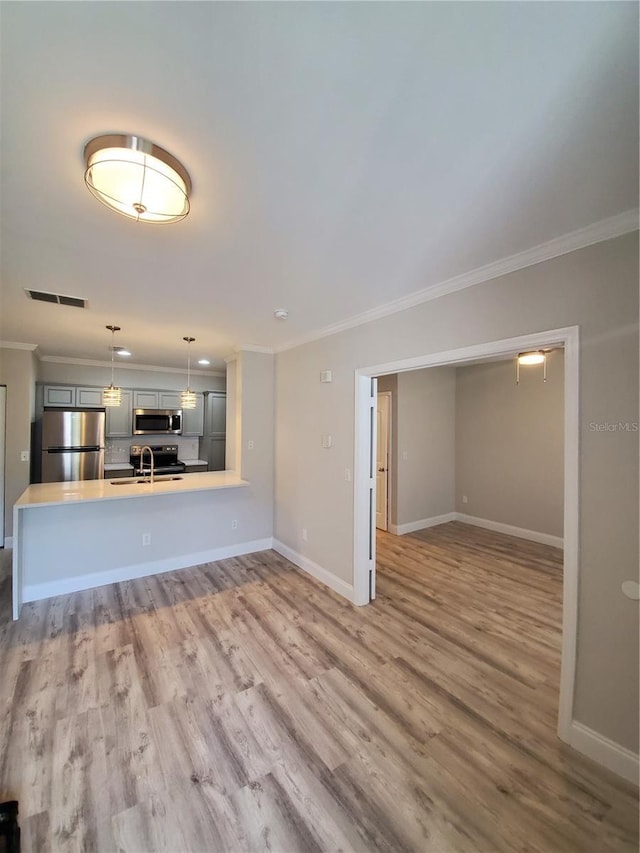 unfurnished living room with sink, hardwood / wood-style flooring, and ornamental molding