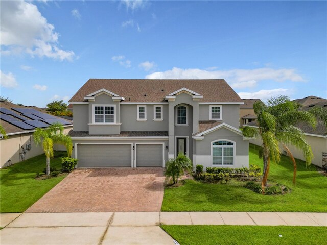 view of property with a front yard, a garage, and solar panels