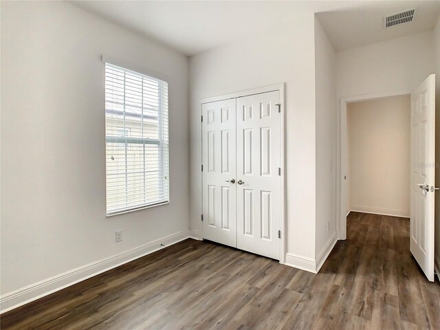 unfurnished bedroom with multiple windows, a closet, and wood-type flooring