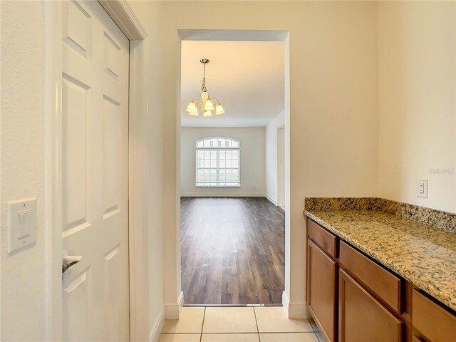 interior space featuring a notable chandelier, light hardwood / wood-style floors, light stone counters, and decorative light fixtures