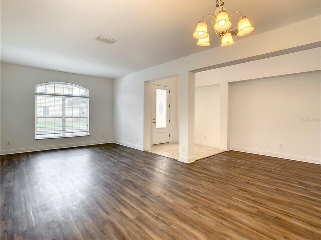 unfurnished living room featuring an inviting chandelier and hardwood / wood-style flooring