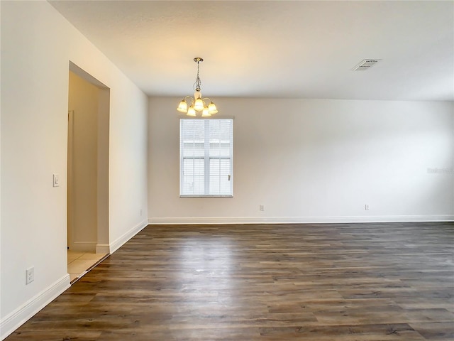 spare room with a notable chandelier and dark tile floors