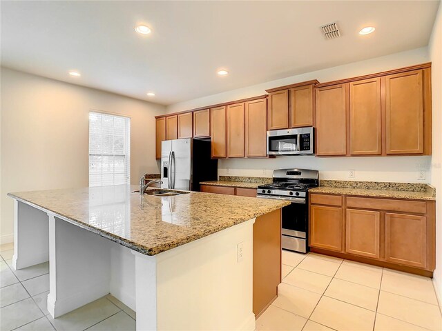 kitchen with a center island with sink, light tile flooring, sink, and appliances with stainless steel finishes