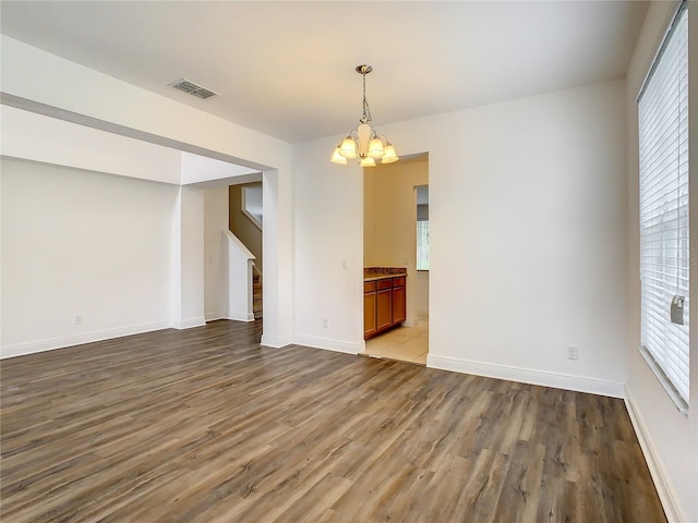 unfurnished room featuring a notable chandelier, a wealth of natural light, and wood-type flooring