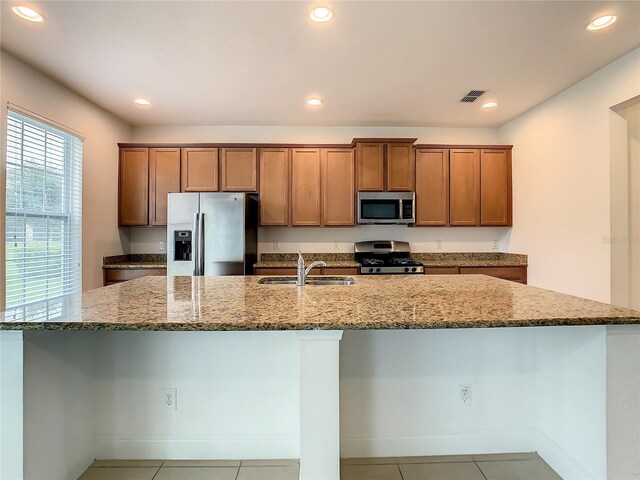 kitchen featuring stainless steel appliances, sink, stone counters, and light tile flooring