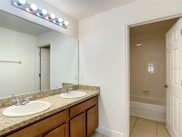 bathroom with tile floors, dual vanity, and tiled shower / bath