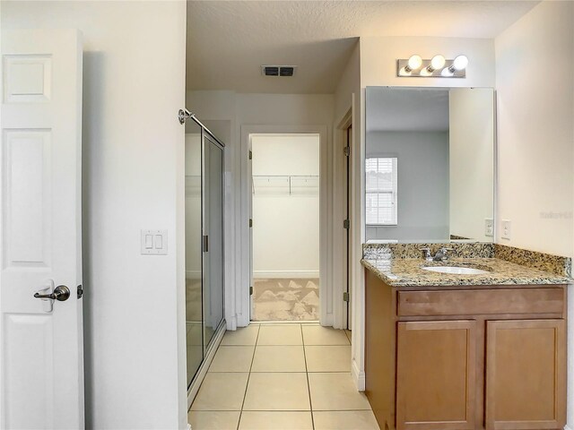 bathroom with an enclosed shower, vanity, and tile floors