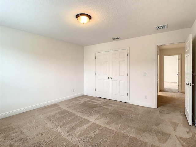 unfurnished bedroom with carpet, a closet, and a textured ceiling